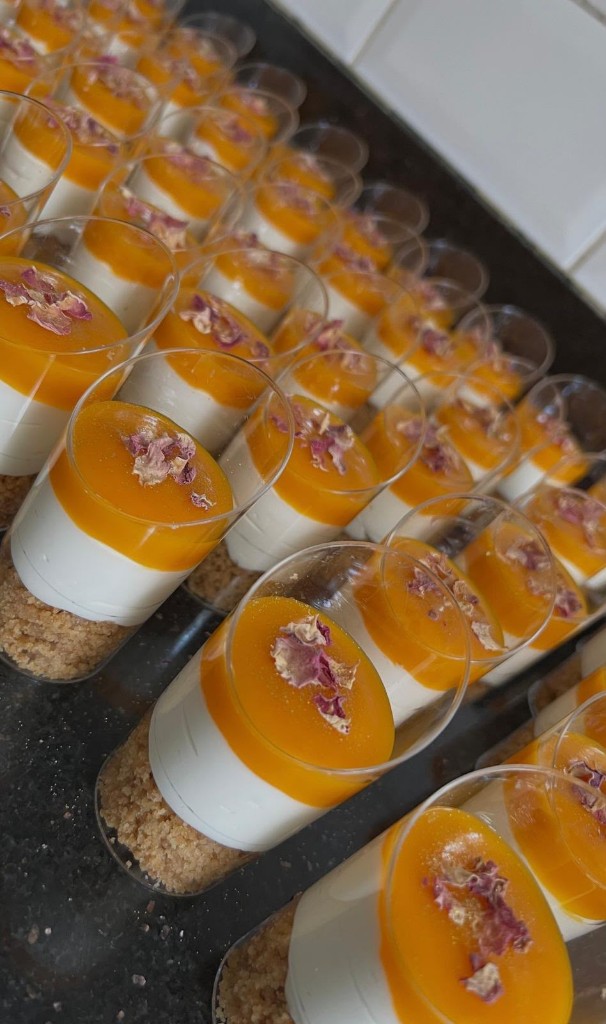 Mini dessert cups with biscuit base, cream and mango topping