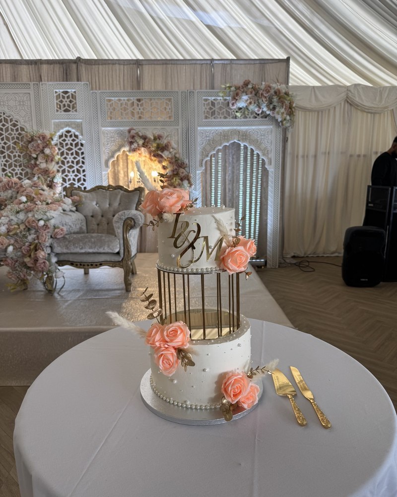 Two-tier wedding cake with mirrored gold birdcake stand, peach roses and L&M monogram